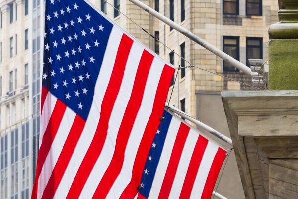 Mehrere US-amerikanische Flaggen hängen vor Gebäuden in der Wall Street in New York.