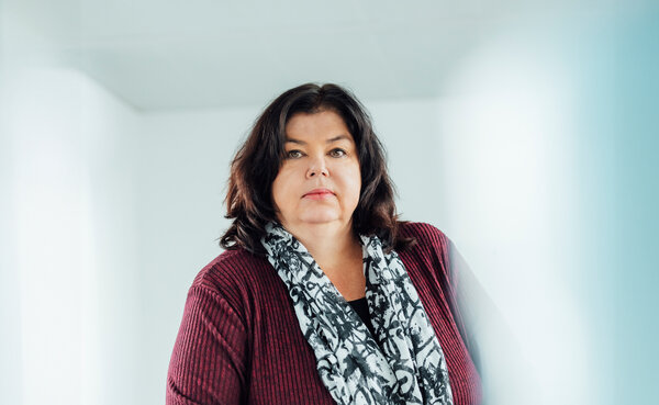 A portrait photograph of a woman sitting behind an office desk wearing a black and white patterned scarf.