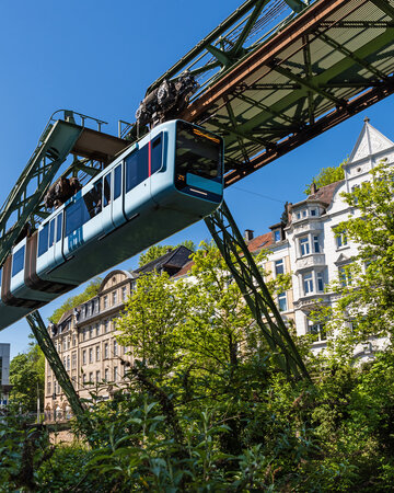 Wuppertal Suspension Railway running on an elevated track between trees and buildings in the Bergisches Städtedreieck region.