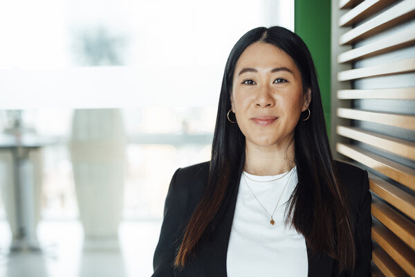 A portrait photograph of a woman wearing a white blouse and a black blazer. She is wearing a gold necklace.