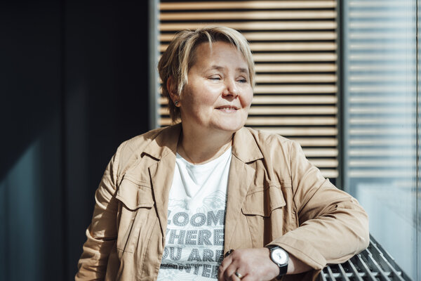 A portrait photograph of a woman wearing a shirt and a summer jacket. Her gaze is directed to the side.